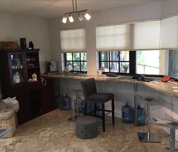 living room wall with counter top and bar stools around the wall underneath windows