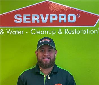 Man standing in front of green wall with SERVPRO logo.