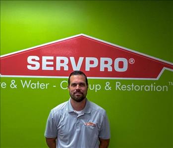 Man standing in front of green wall with SERVPRO logo on it.