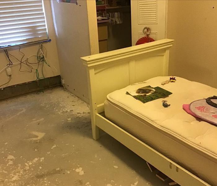 bedroom with white furniture and dark flooring that has puddled water through out