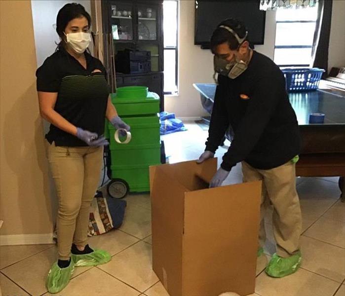 SERVPRO employees are packaging a customers belongings into a box with care